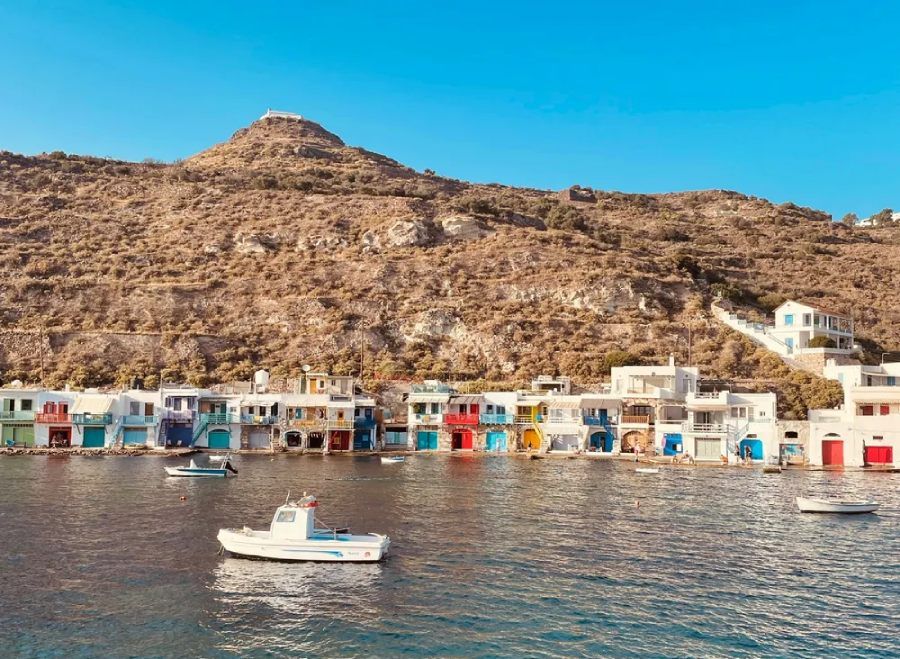 Fila de casas-embarcadero tradicionales de colores vivos frente al mar en Klima, isla de Milos