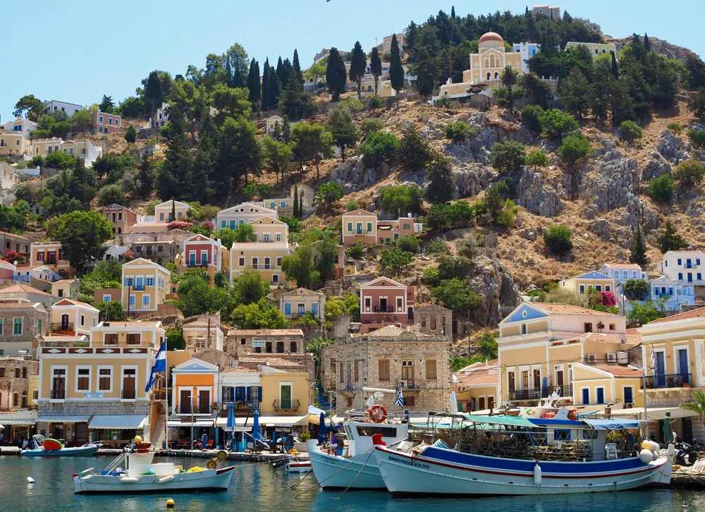 Casas neoclásicas de colores en la ladera del puerto de Symi, Grecia, con barcos de pesca en primer plano