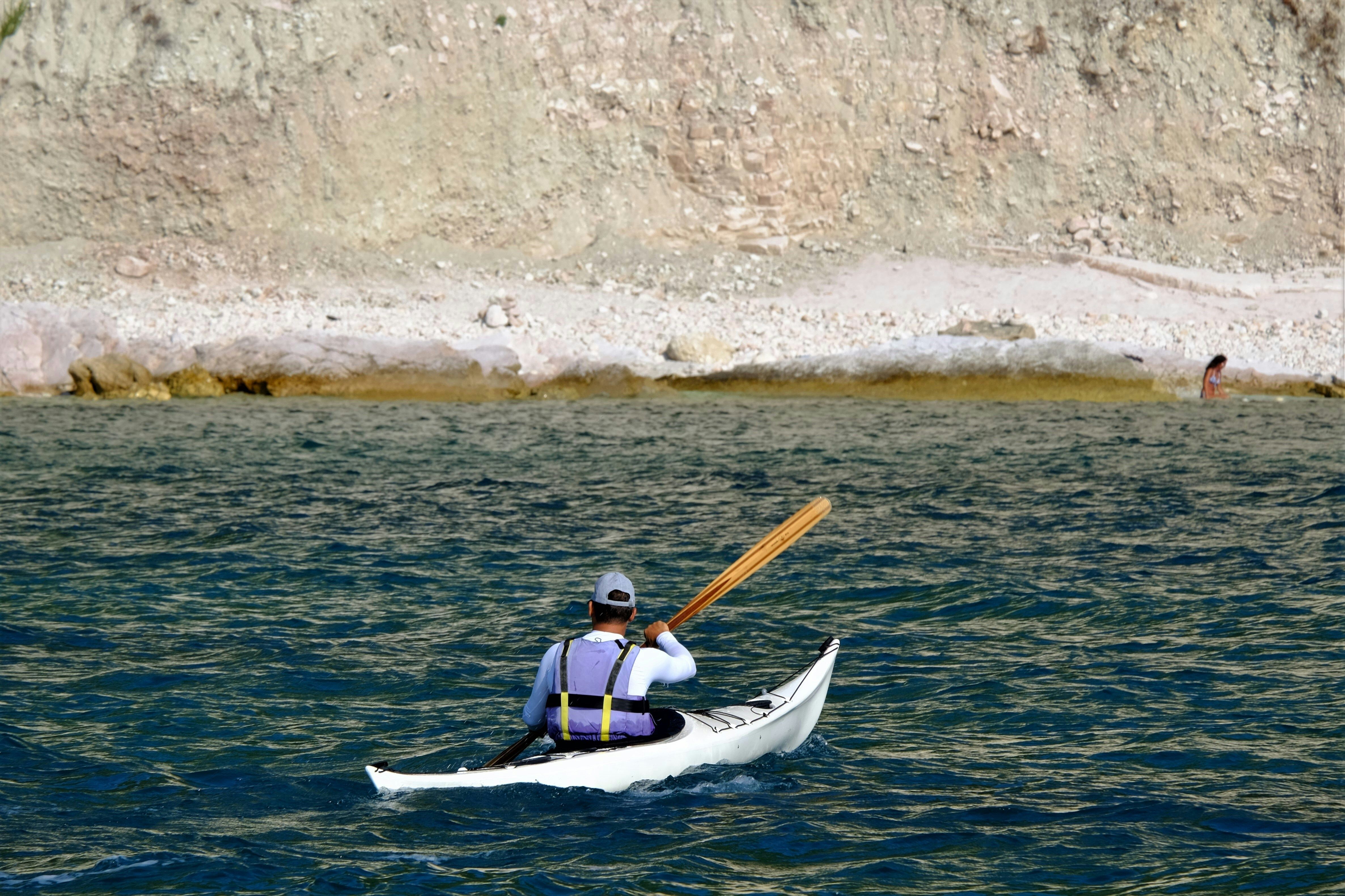 homme de dos dans un kayak mer et falaise blanche
