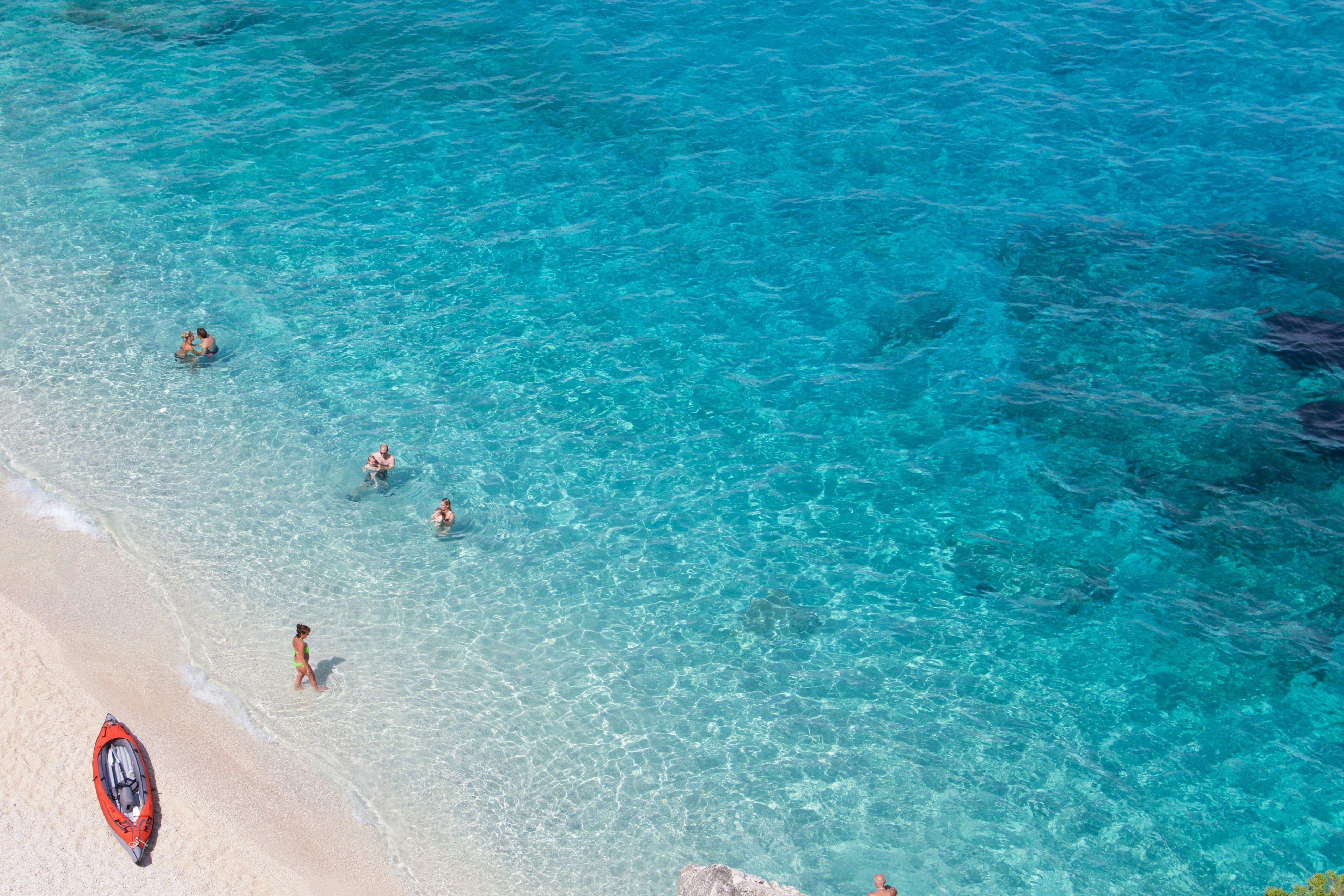 Mare blu trasparente bagna una spiaggia sabbiosa della Sardegna.