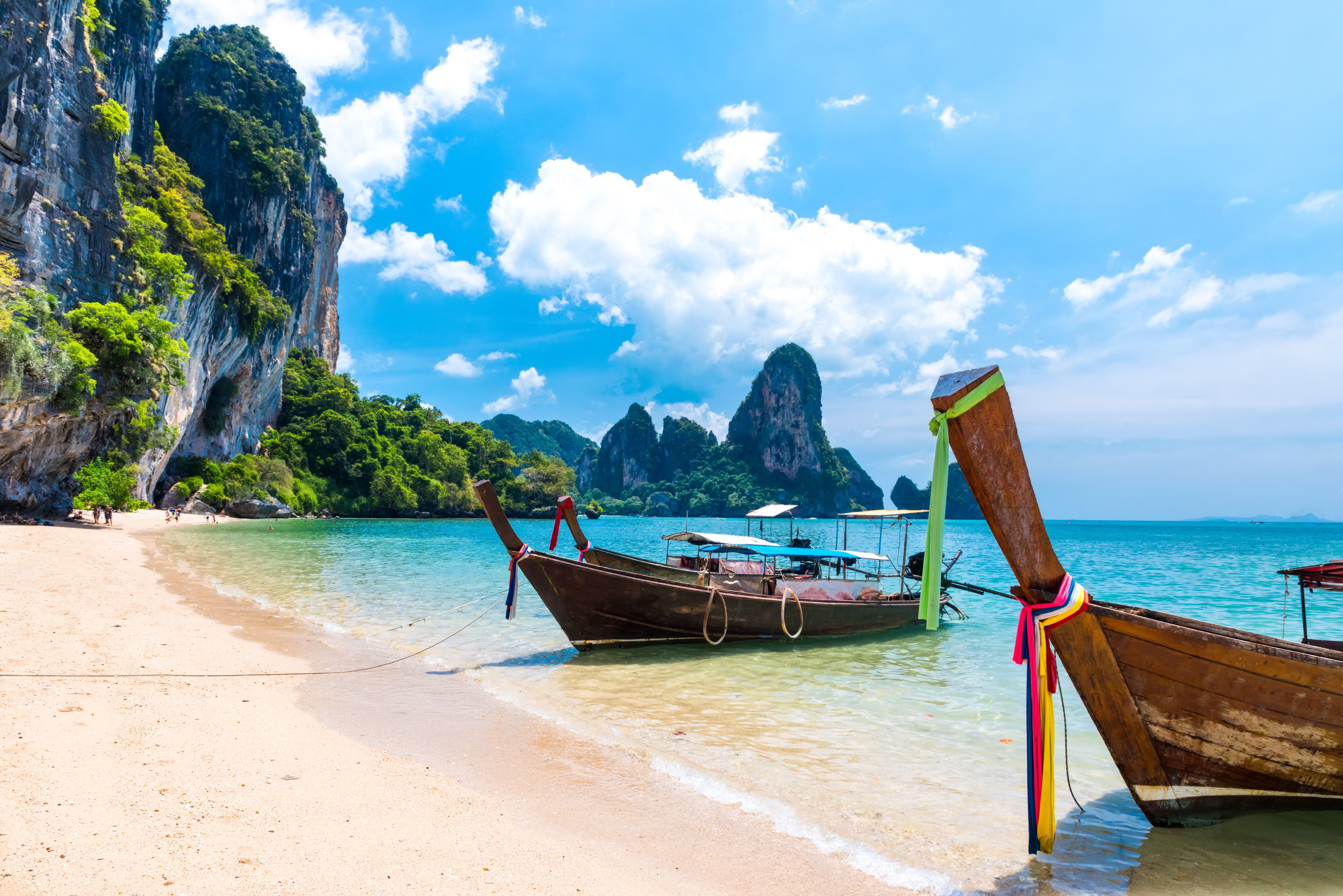 tailboats in a bay with limestone cliffs in Krabi