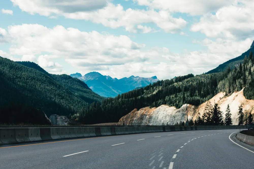 Eine kurvige Straße führt durch eine beeindruckende Berglandschaft.