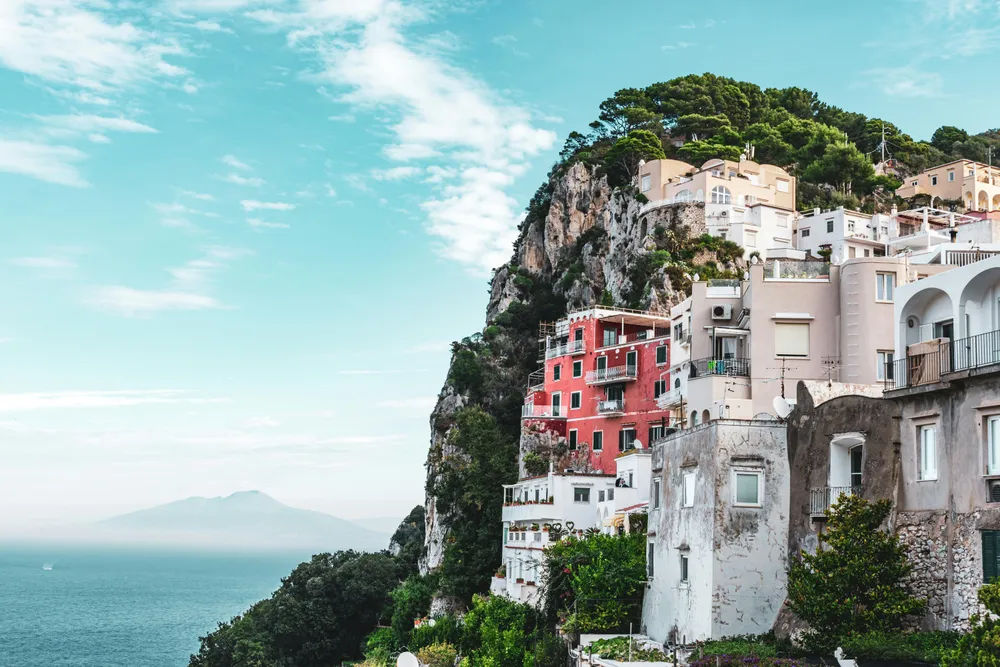 Die Häuser auf Capri scheinen an einem Felshang zu schweben. Im Hintergrund sieht man das blaue Meer.