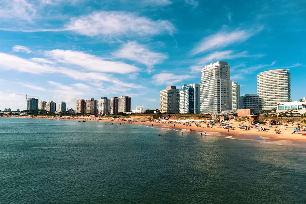 the golden beach in Punta del Este with buildings rising into a blue sky