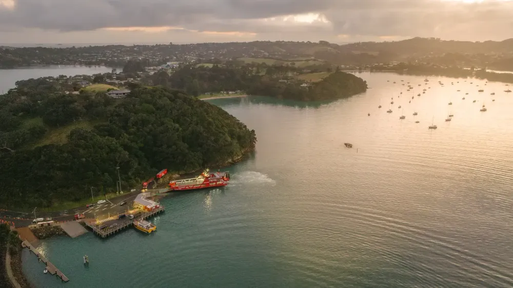 Sunset view over Kennedy Point, Waiheke Island, with ships on the water, a SeaLink vessle leaving the port.