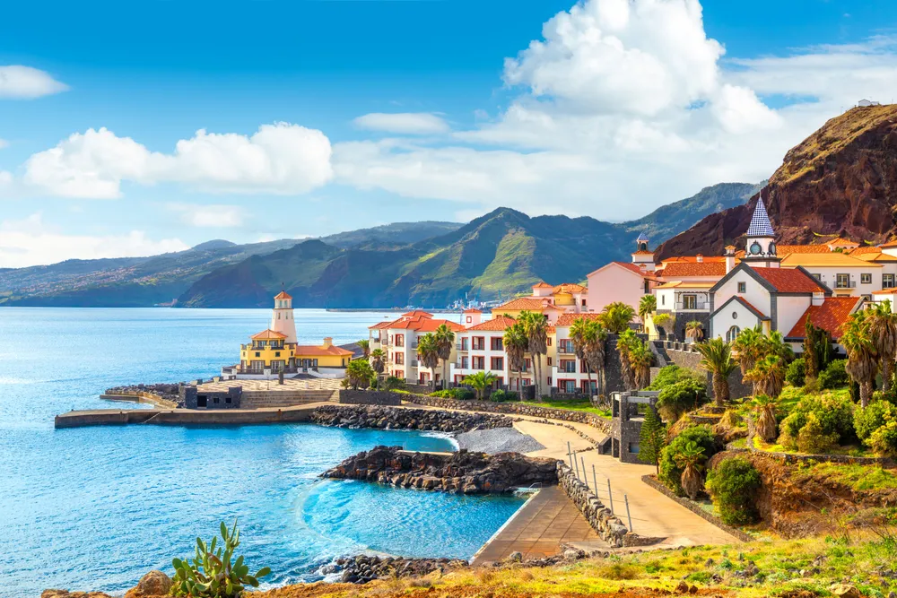 houses and greenery along the waterfront in Madeira with mountains behind