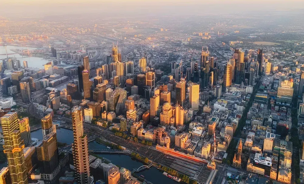 Die Skyline von Melbourne ist am Abend in ein goldenes Licht getaucht. Die Aufnahme wurde aus der Luft gemacht.