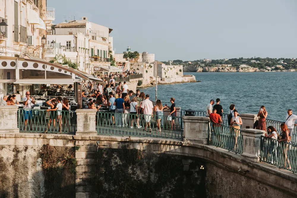 Turisti affollano le strade di Ortigia (Sicilia) e si godono il panormala da uno dei ponti che collegano l'isola a Siracusa.
