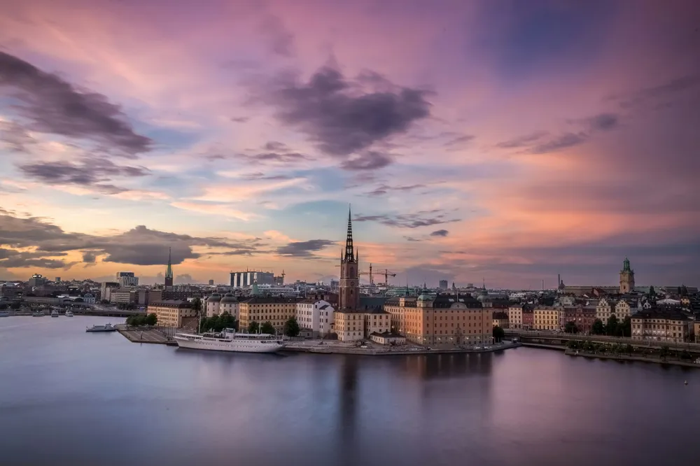 Fluss-Promenade einer Stadt bei Sonnenuntergang, lila, blauer und orangener Himmel.