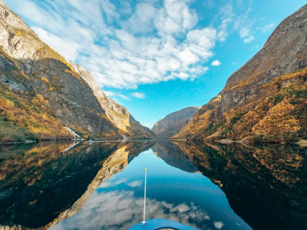 Ein atemberaubender Blick auf den Nærøyfjord in Norwegen. Das glasklare Wasser spiegelt den blauen Himmel, links und rechts erheben sich die Berge.