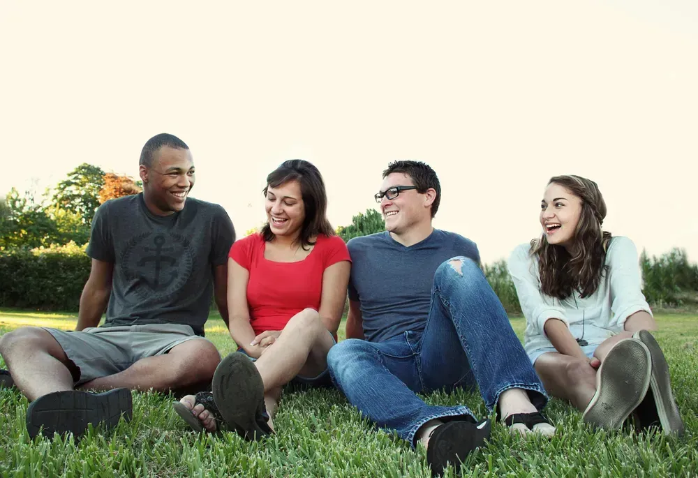 a group of friends sat on the grass laughing together
