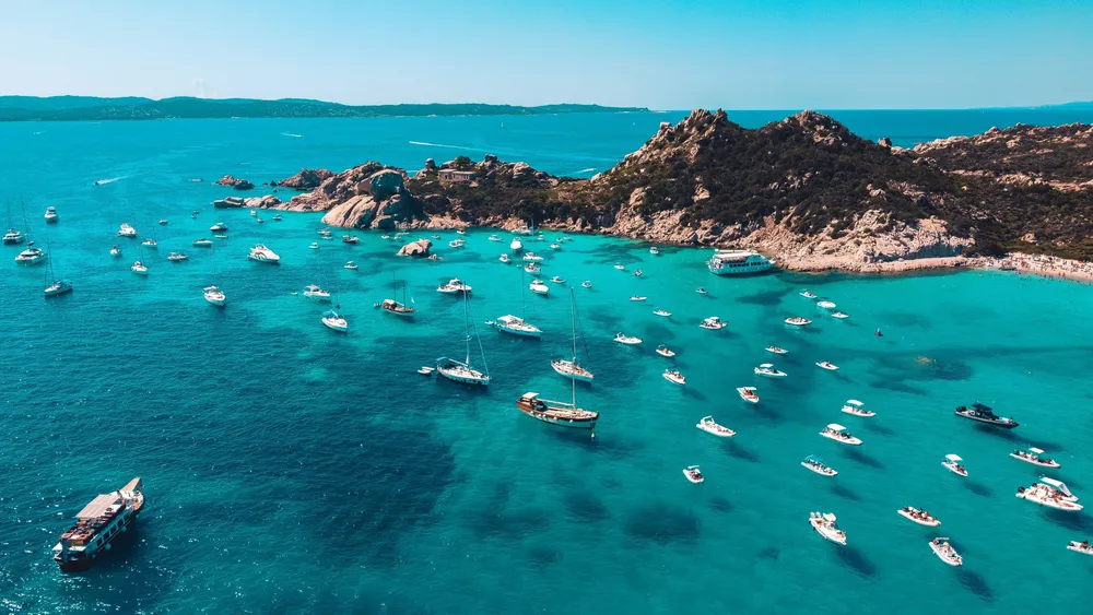 Barche a vela in una baia turchese della Sardegna.