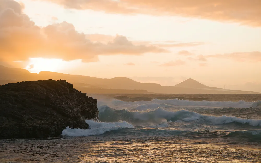vagues avec ecume blanche a cote de rocher volcanique
