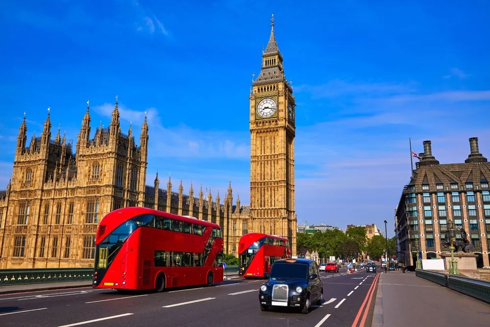 Vista del Big Ben en Londres con autobuses rojos de dos pisos y tráfico típico.