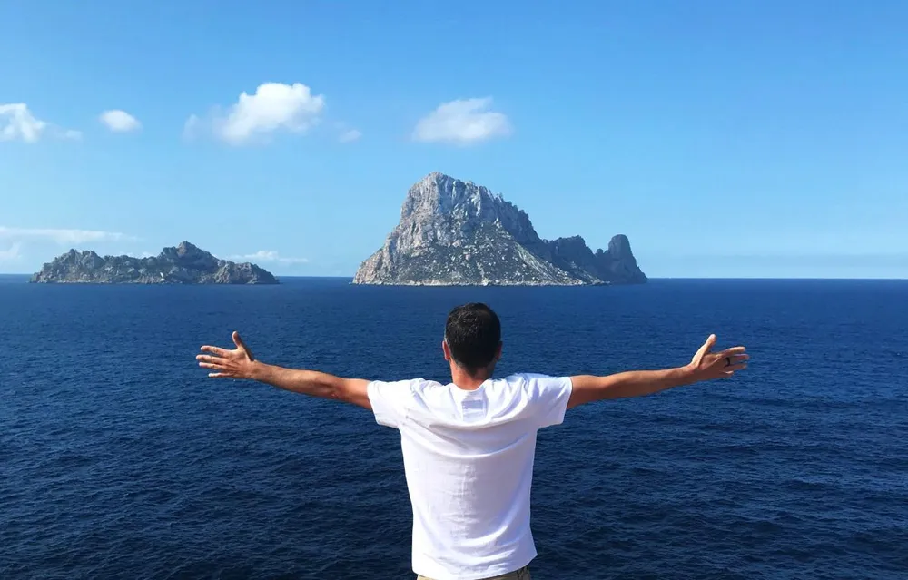 Viajero contemplando Es Vedrà en Ibiza desde un mirador frente al mar