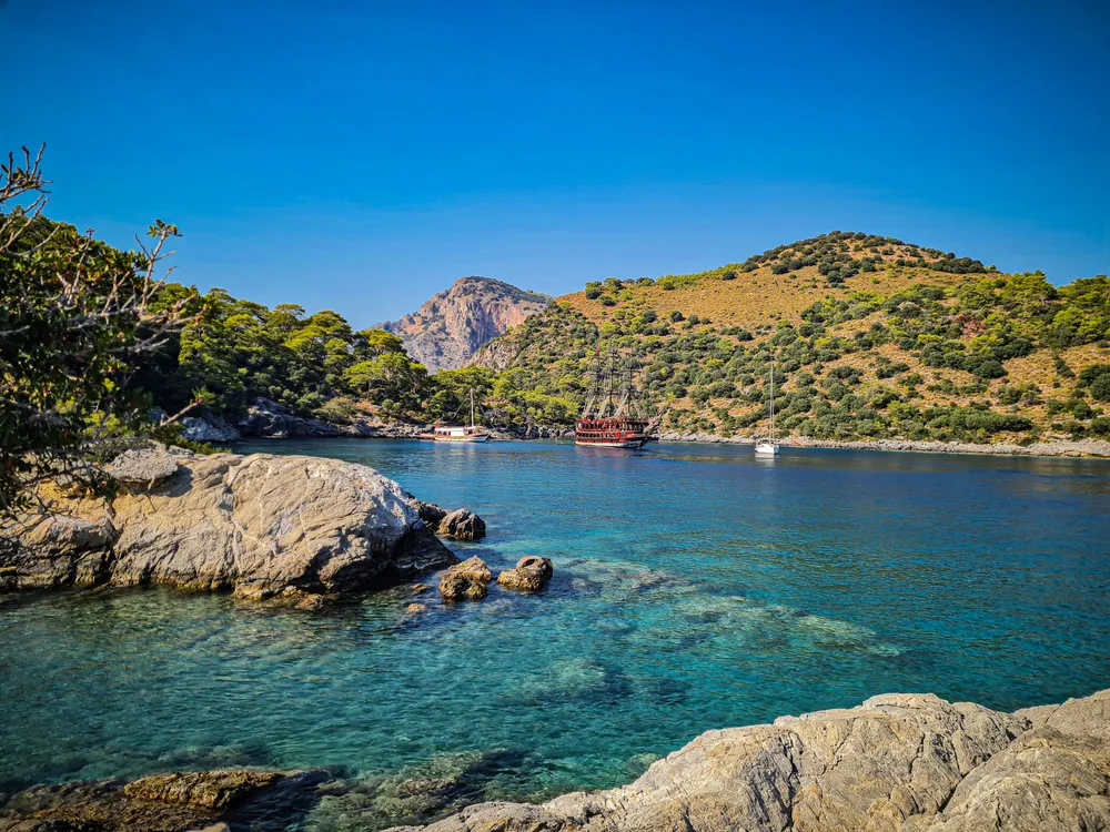 crique avec rochers mer turquoise et collines verdoyantes