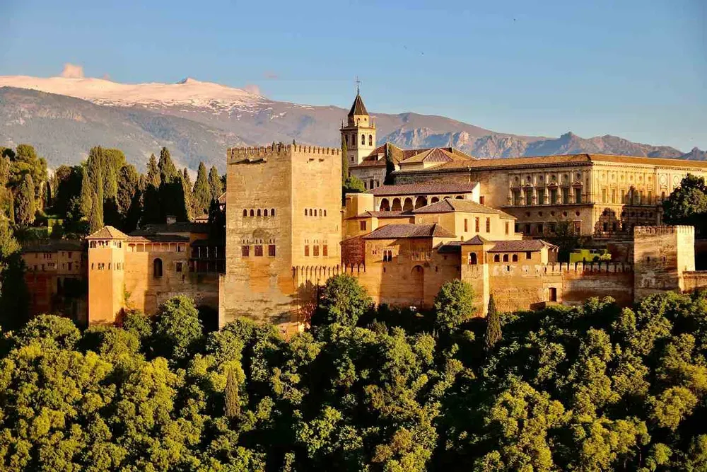 L'Alhambra con la Sierra Nevada sullo sfondo: un'immagine iconica di Granada che in inverno si tinge di luce dorata e neve sulle montagne.