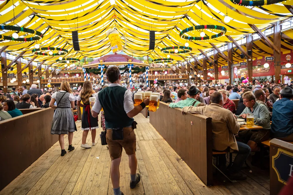 A man in traditional Bavarian dress carrying Maßes of beer into the tent at Theresienwiese