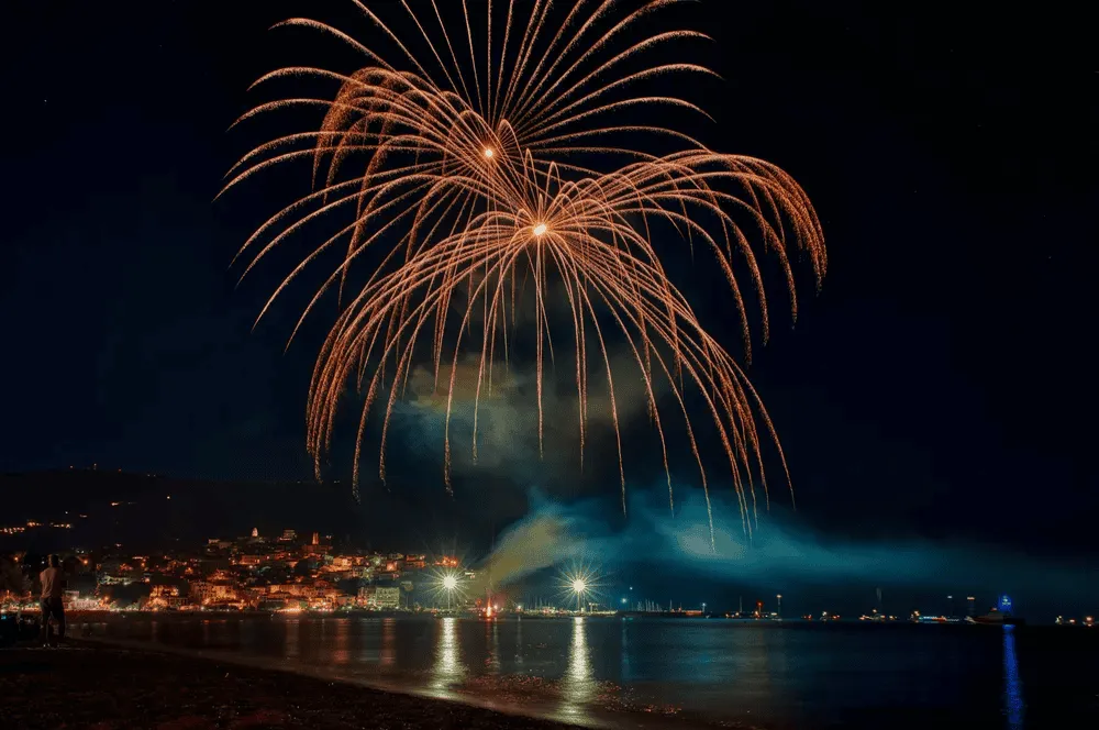 feu d'artifice le soir au dessus de fleuve avec village au fond