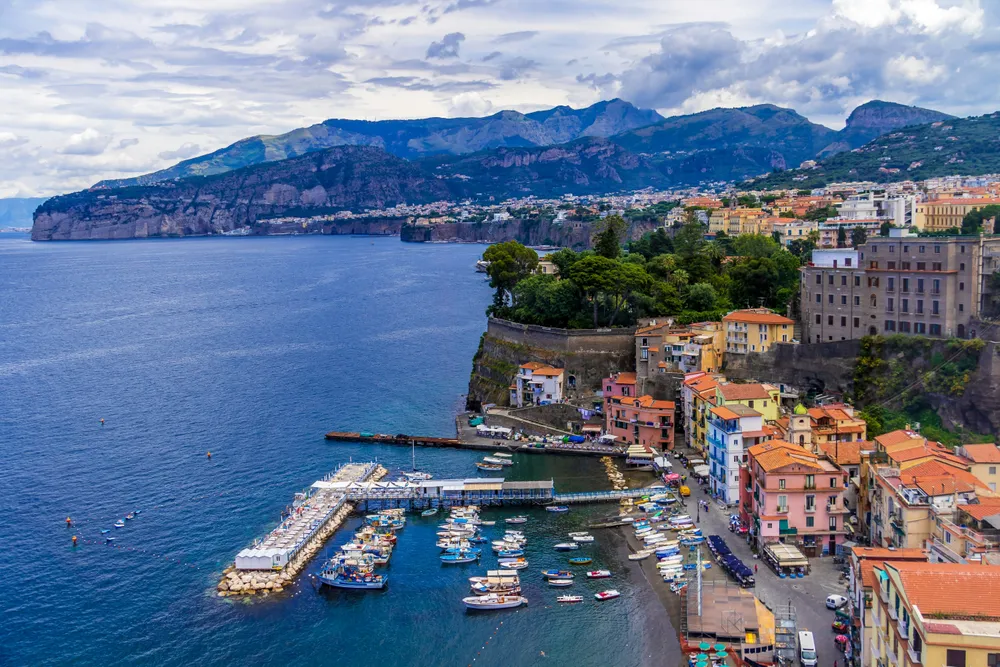 port de sorrente avec bateaux de peche batiments cote et vue sur montagne au loin