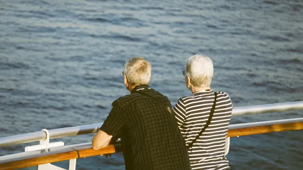 a man and woman on a ferry looking out to sea