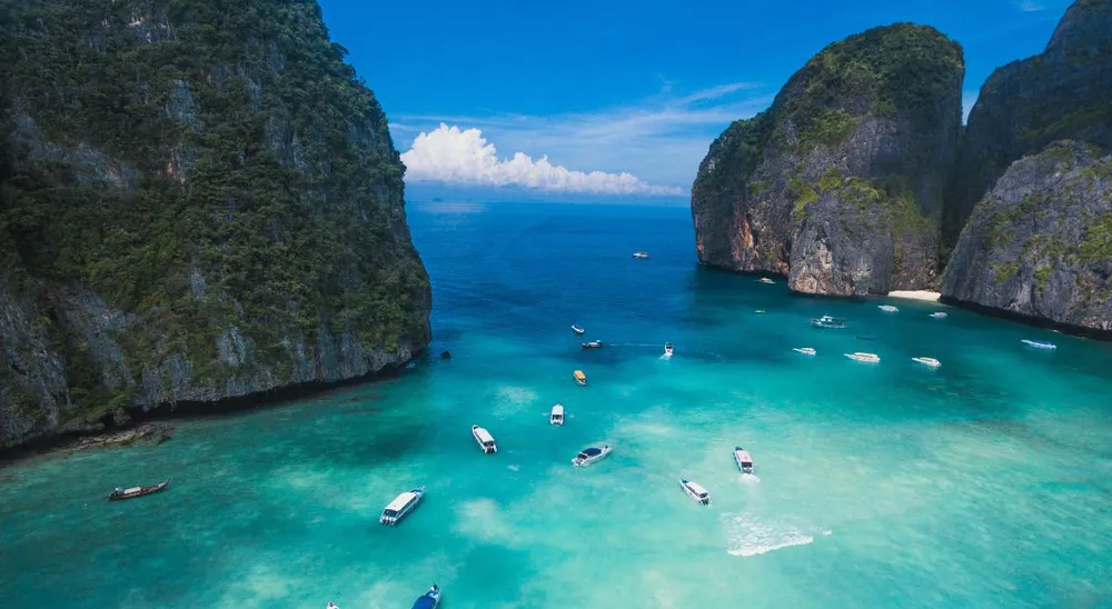 Lanchas y barcos pequeños en aguas turquesa frente a los acantilados de Koh Phi Phi