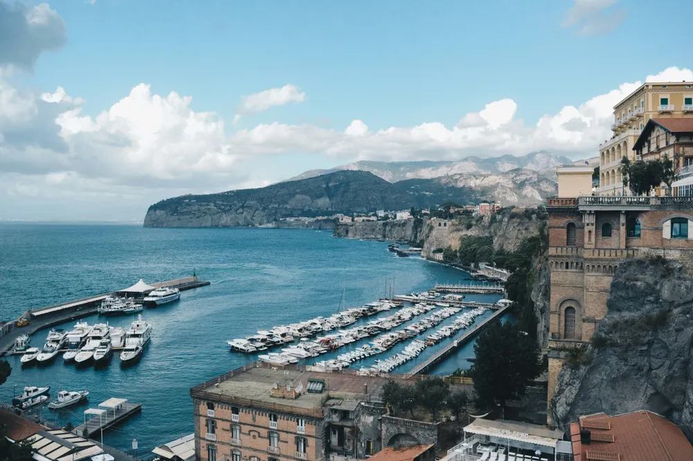 marina avec bateaux blancs batiments et montagne