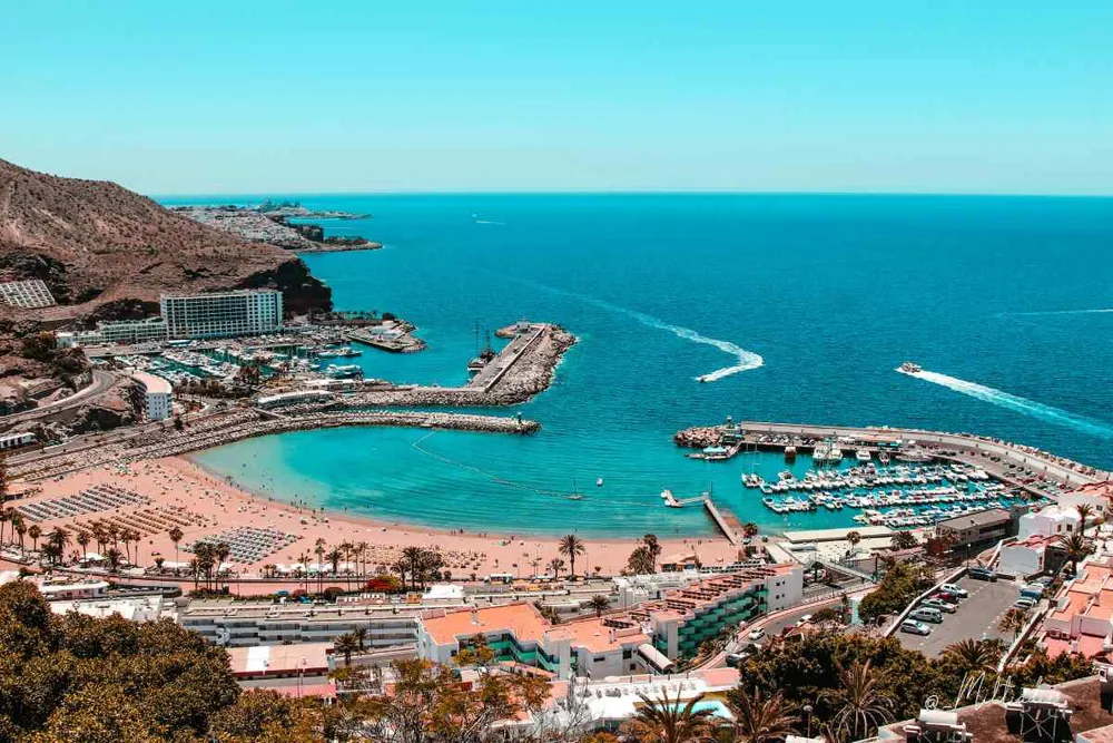 Vista aérea del Puerto Rico de Gran Canaria con su playa, hoteles y puerto deportivo junto al mar.