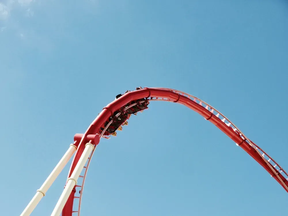 red rollercoaster against a blue sky