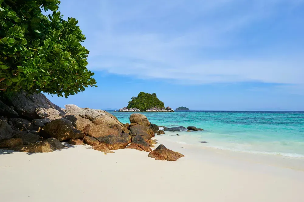 des rochers sur une plage de sable blanc bordée d'eaux turquoise cristallines à Koh Lipe