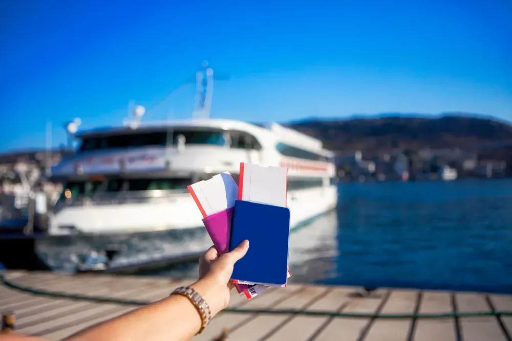 someone holding up 2 passports next to a ferry