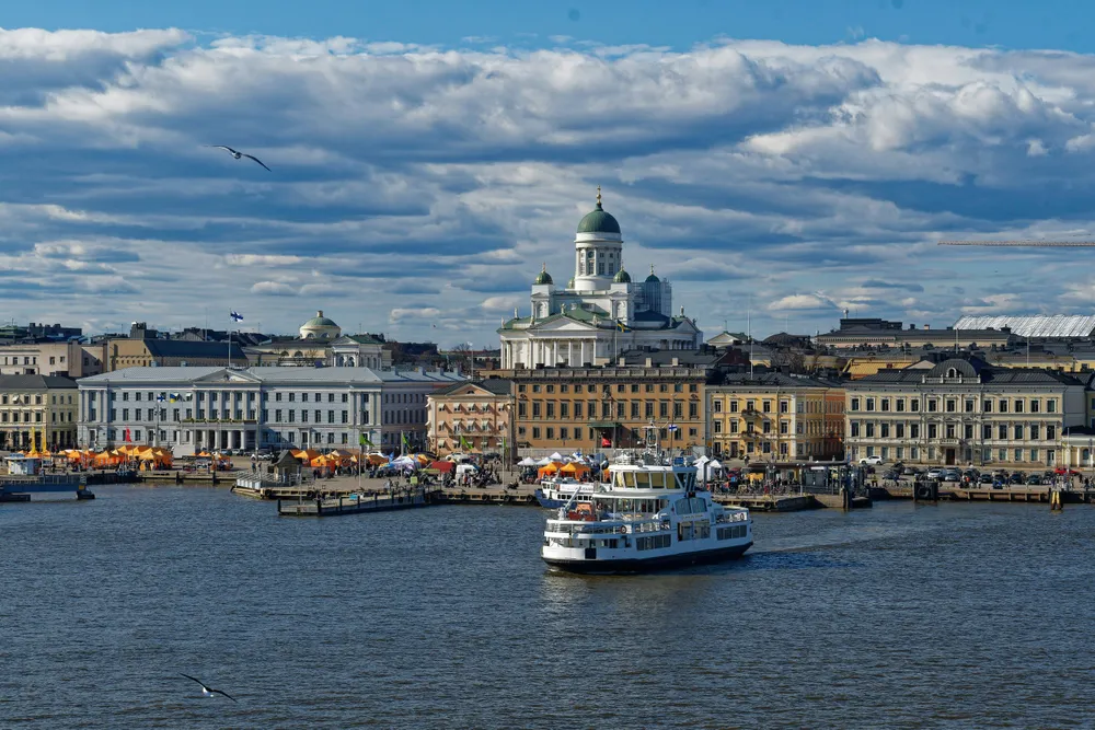 Eine Fähre verlässt den Hafen von Helsinki. Die Sonne scheint, im Hintergrund sieht man die Skyline von Helsinki.