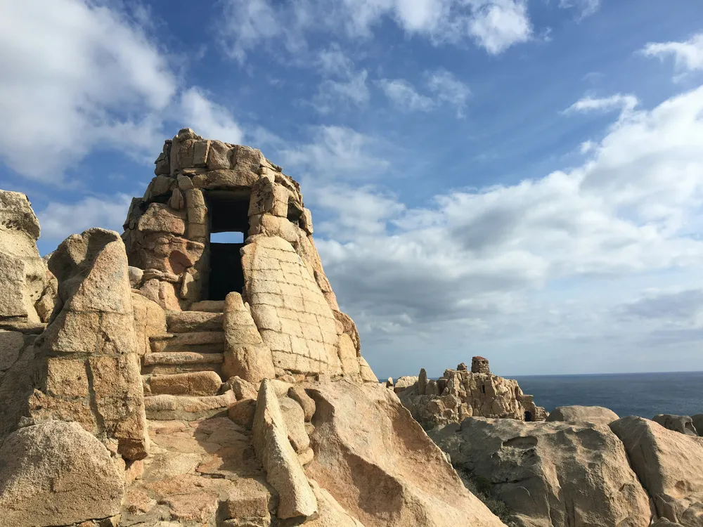 tour en pierre avec rochers sur ciel nuageux