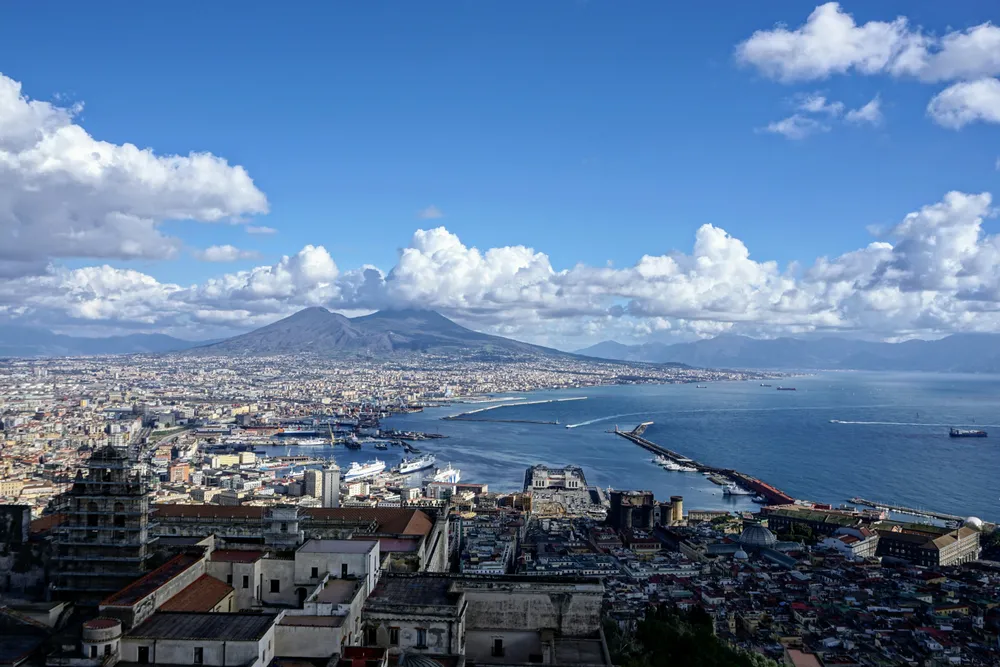 batiments avec mer et volcan au fond