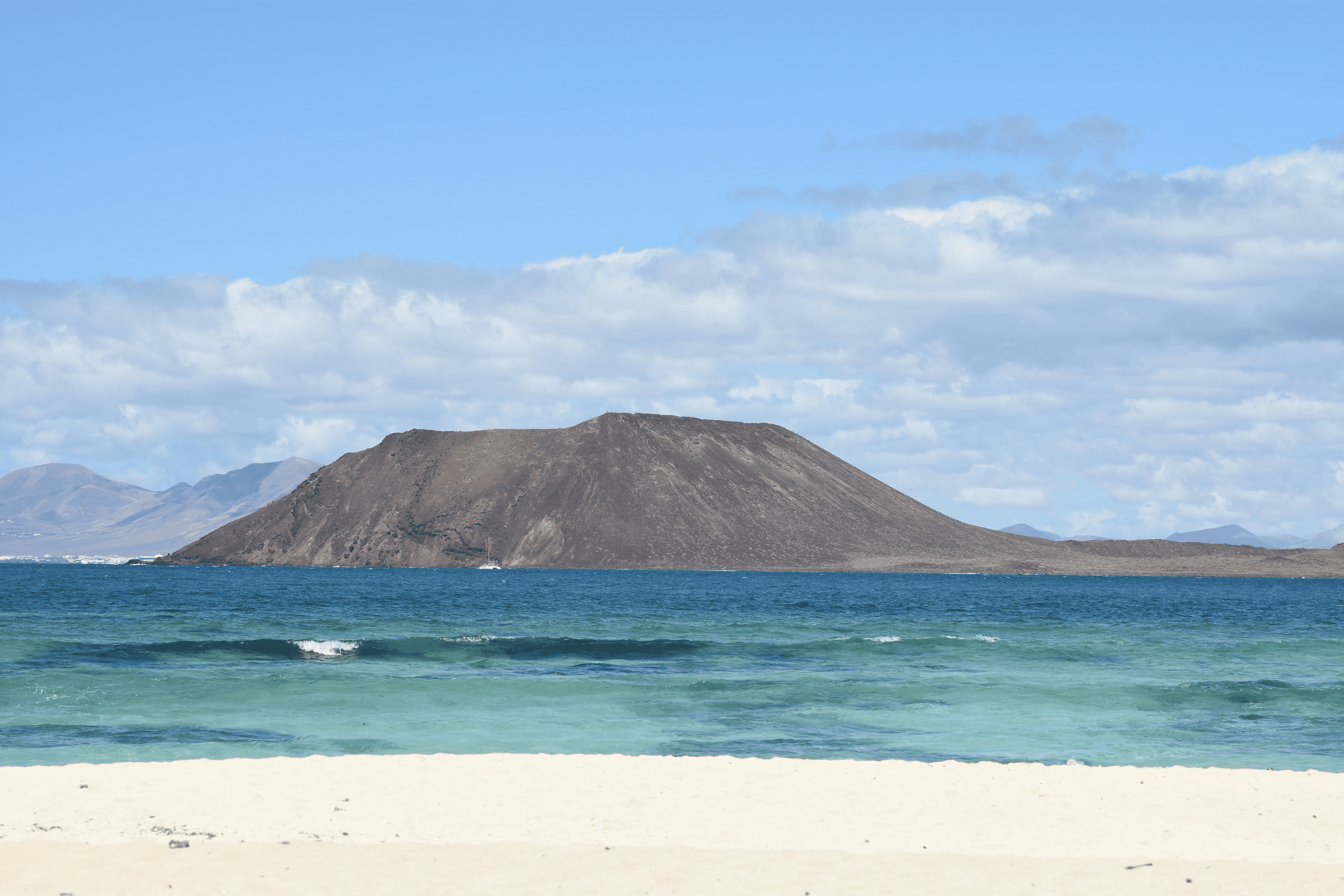 plage avec mer et montagne au fond