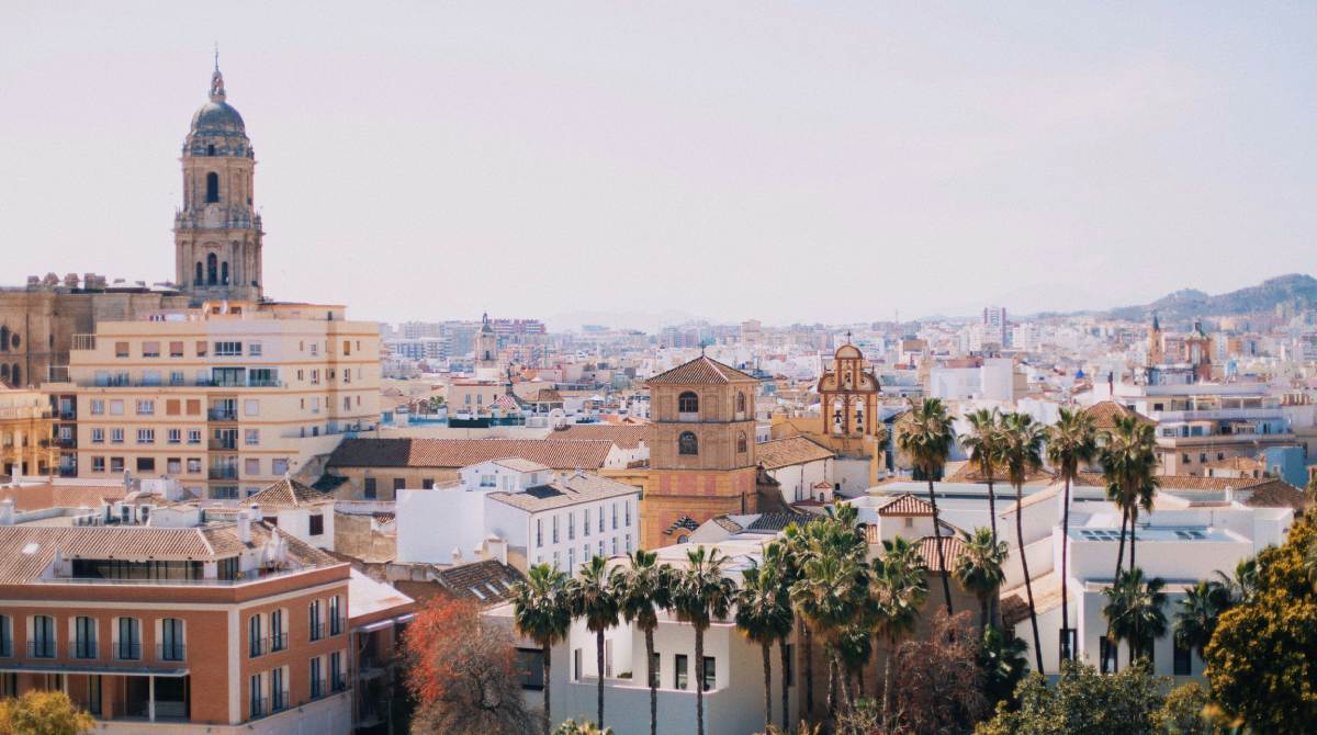 Vista panorámica del centro histórico de Málaga con la Catedral y palmeras, bajo el cielo despejado de la Costa del Sol.