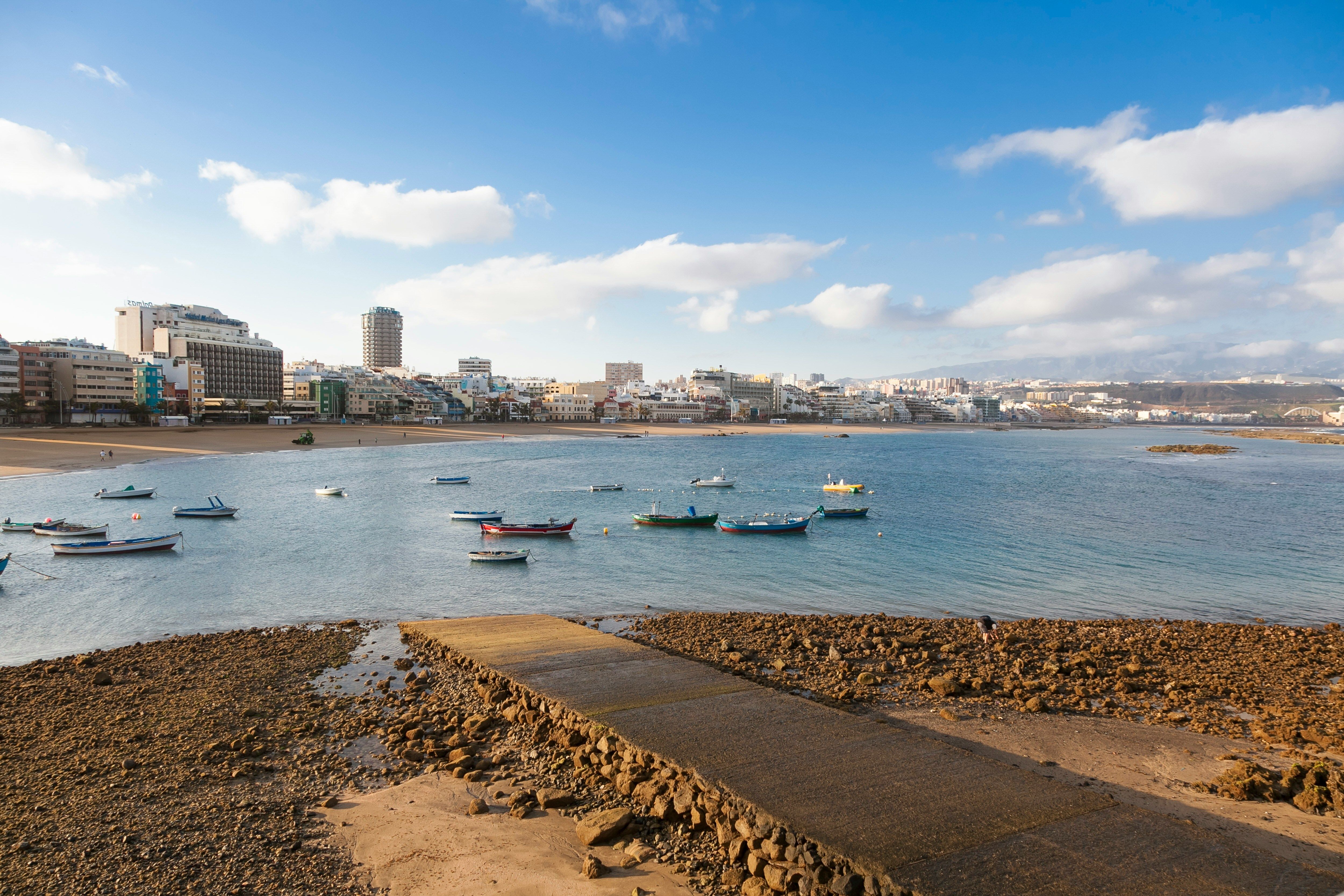 embarcadere sur plage menant a eau avec ville au fond