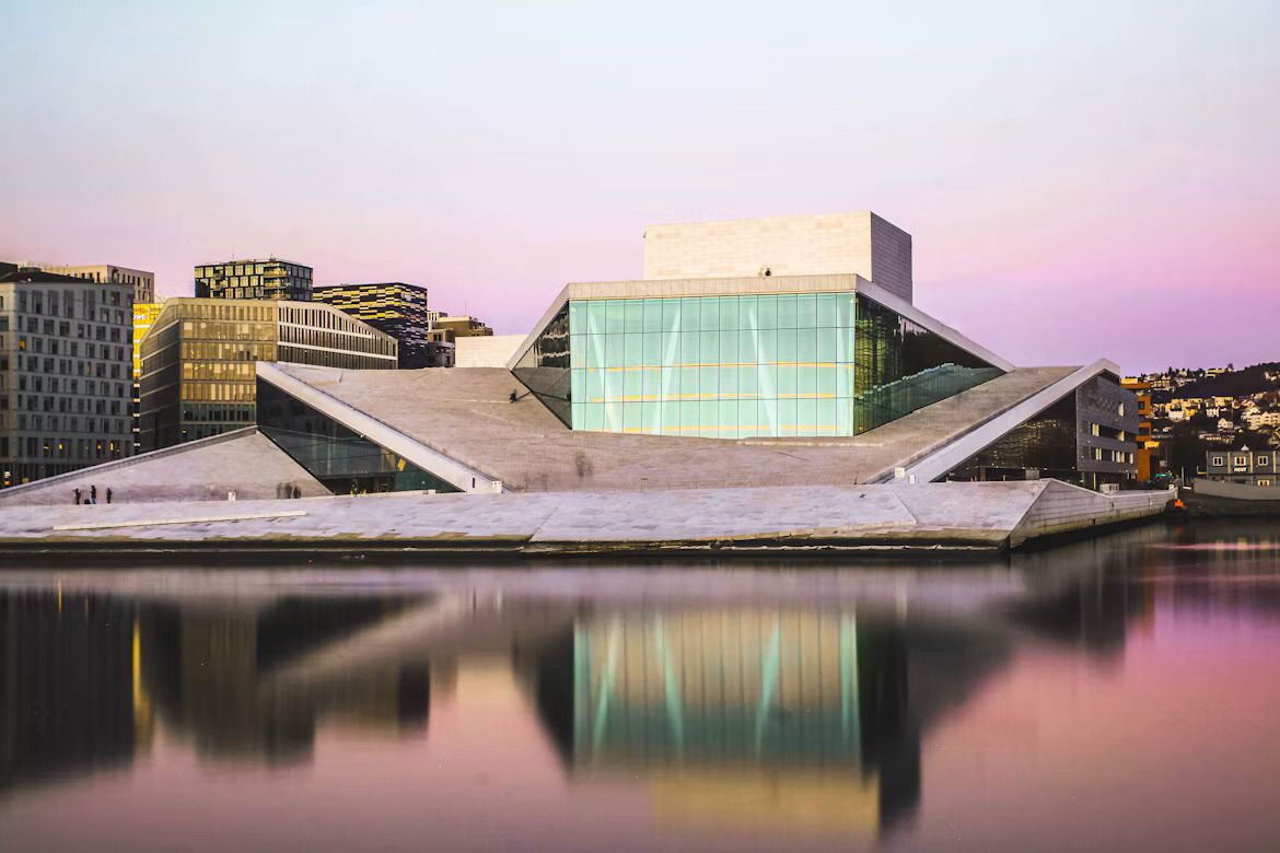 The glass facade of Oslo opera house reflected in the water