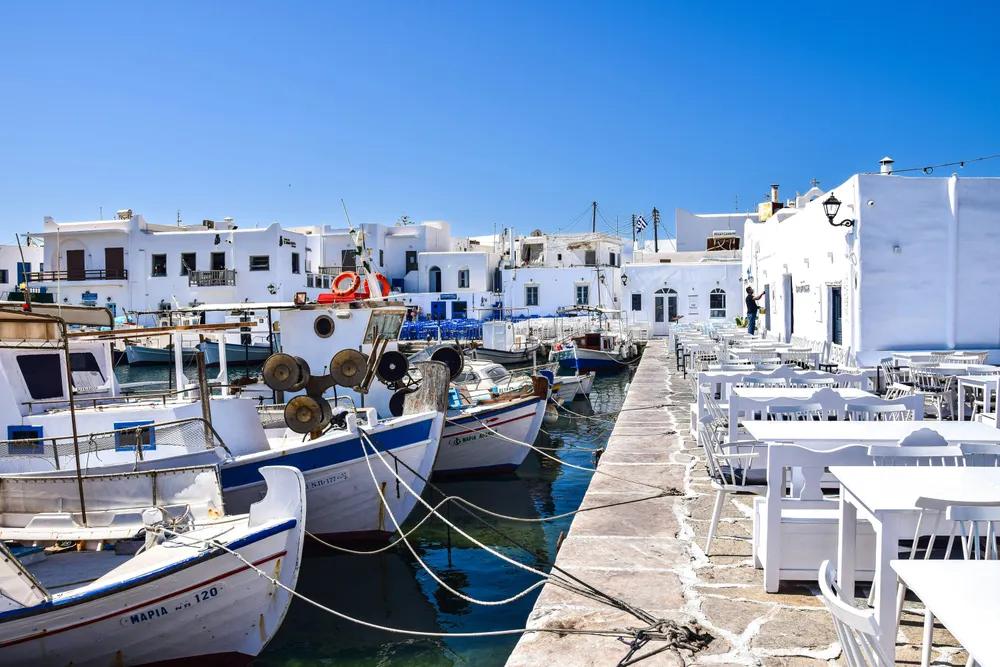 Puerto de Naoussa en Paros con barcos pesqueros y terrazas blancas junto al mar