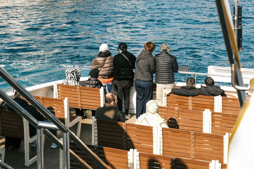 people stood and sat on an outdoor ferry deck