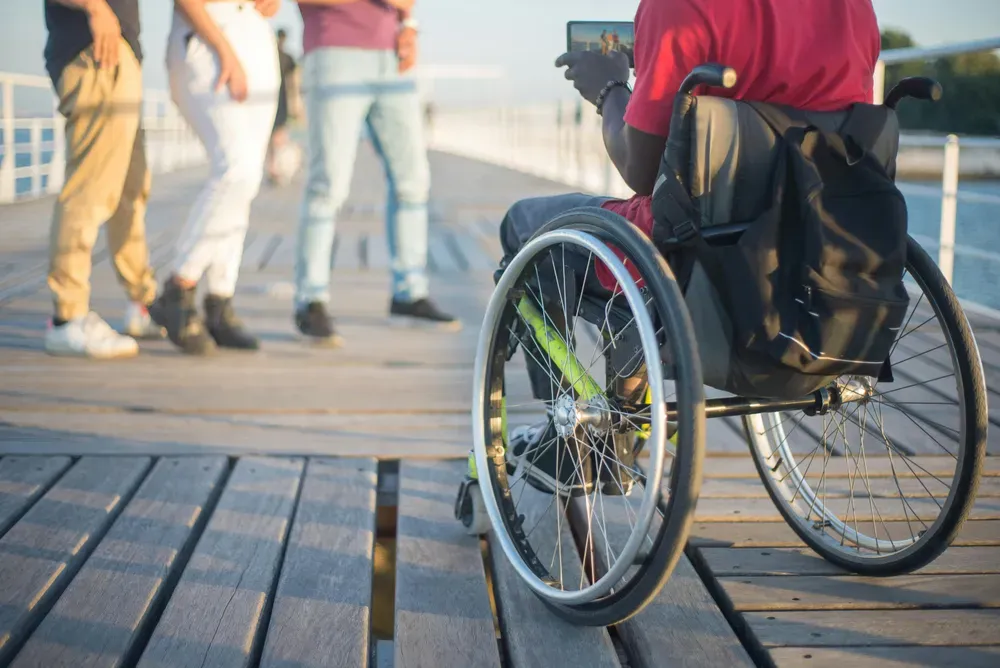 person on a wheelchair taking a photo of 3 people