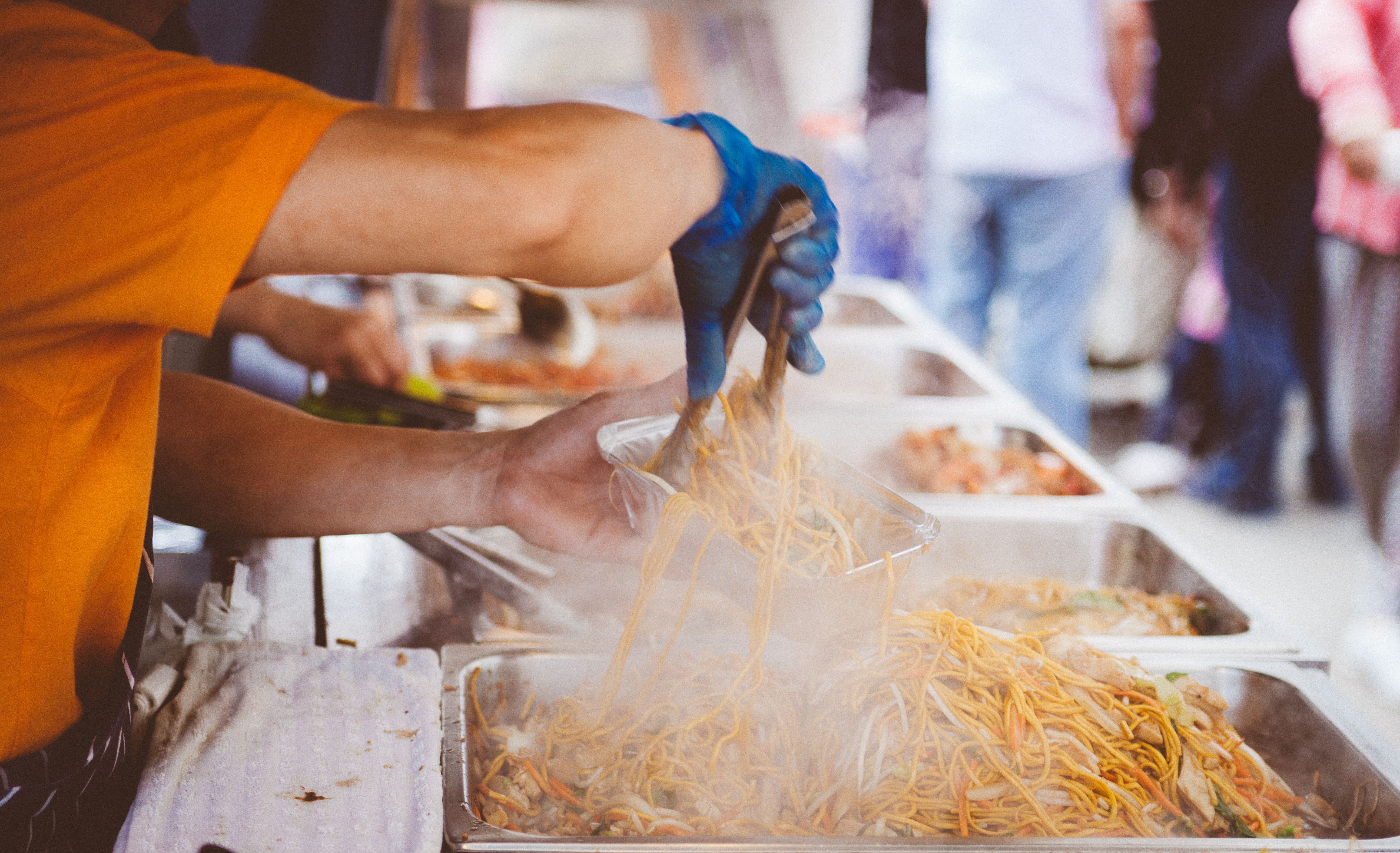 a vendor serving noodles into a container
