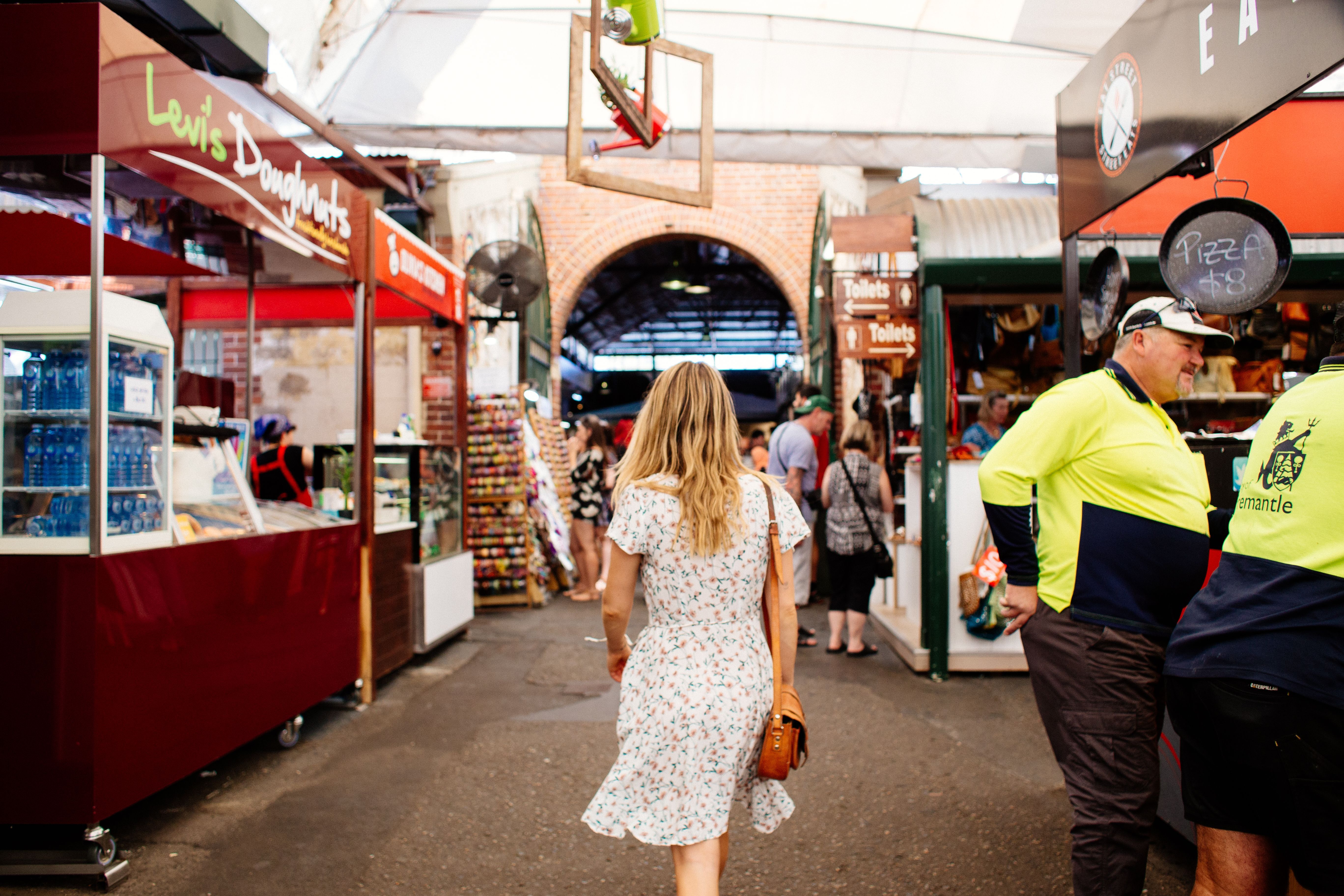 A woman in a floral dress walking through a busy market