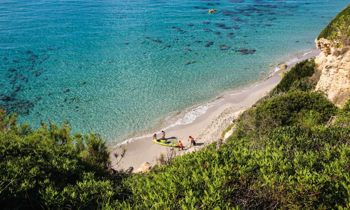Vista aérea de la Playa de Binigaus en Menorca, con arena blanca y aguas turquesas.