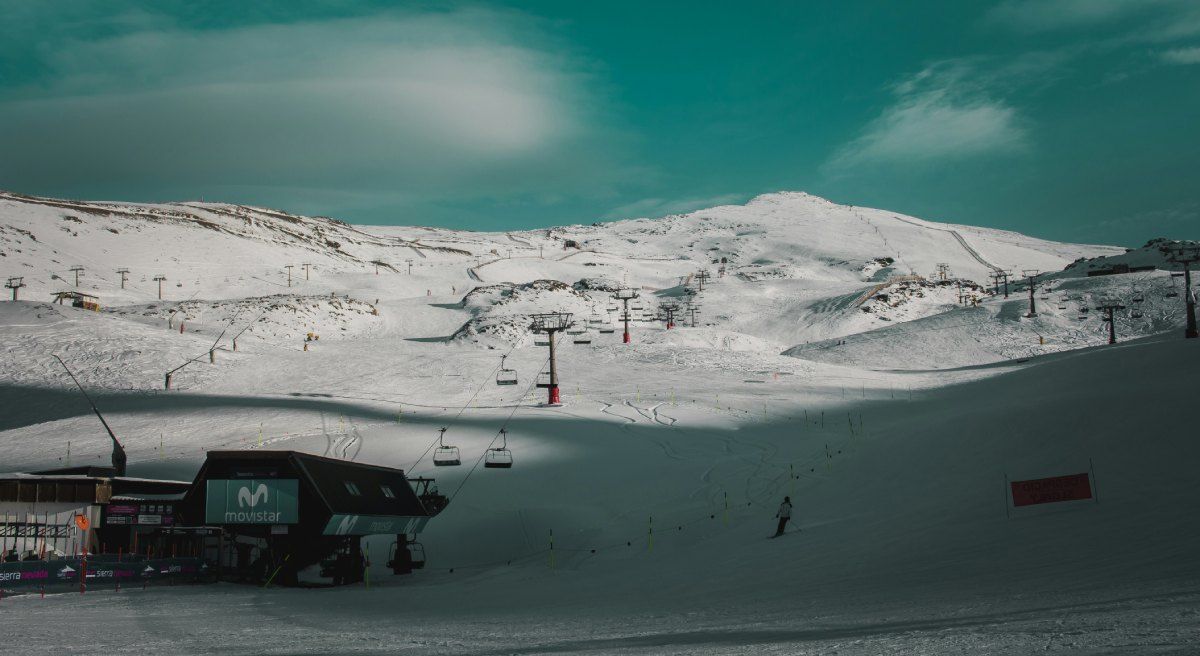Stazione sciistica di Sierra Nevada ricoperta di neve con seggiovie e montagne sullo sfondo in una limpida giornata invernale.
