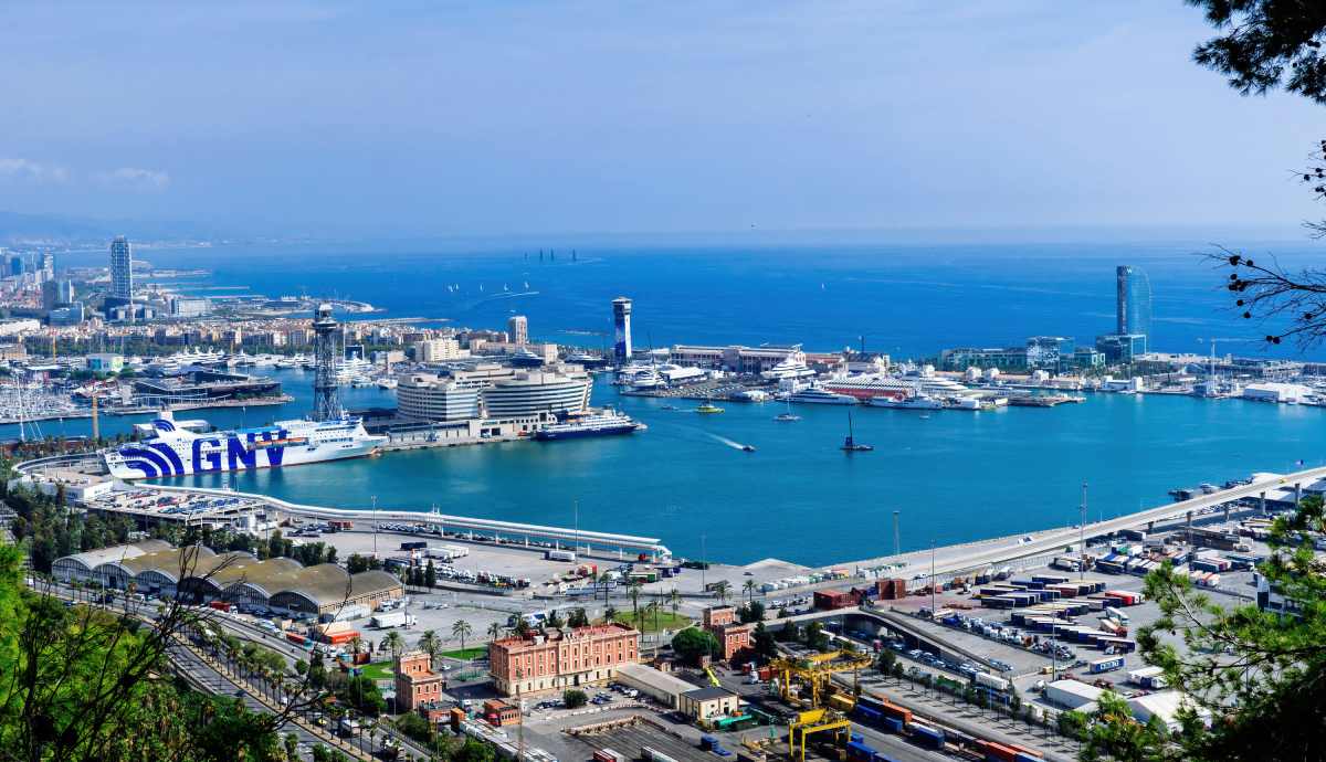Vista panorámica del puerto de Barcelona con ferris y cruceros atracados.