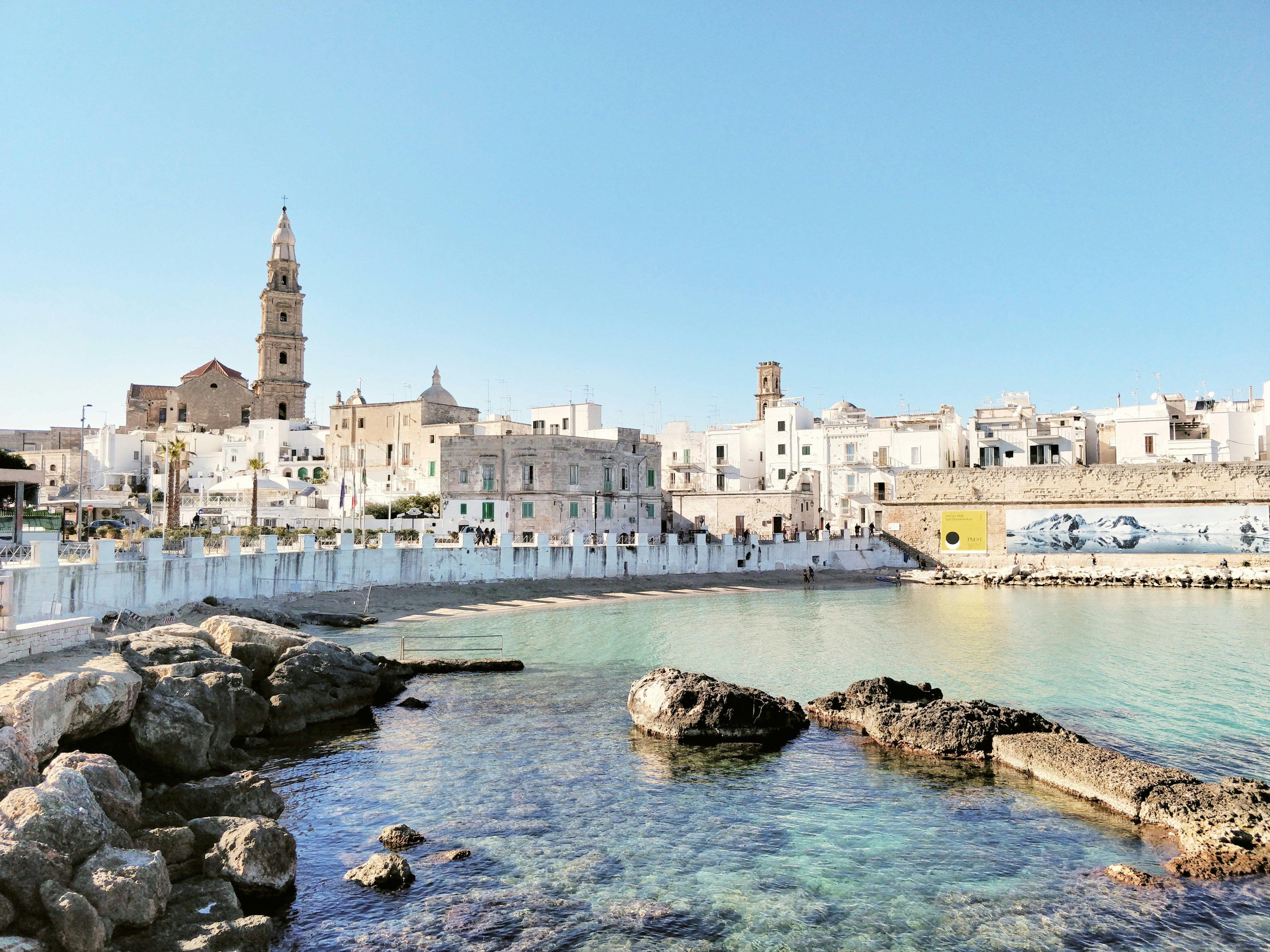rocks in the water by buildings in Bari