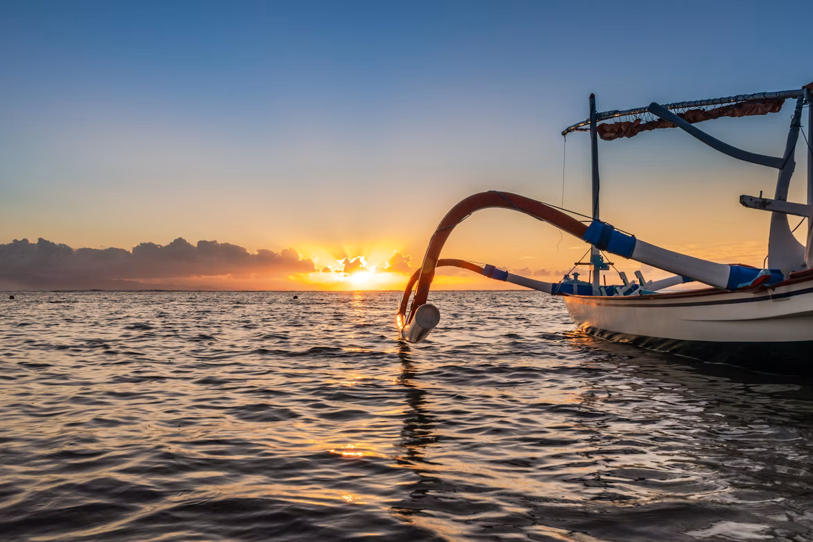 a boat floating in peaceful waters during sunset