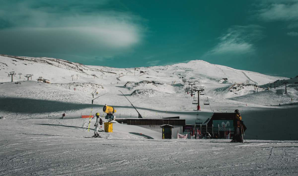 Pistas de esquí en Sierra Nevada con telesillas y esquiadores en una jornada despejada.