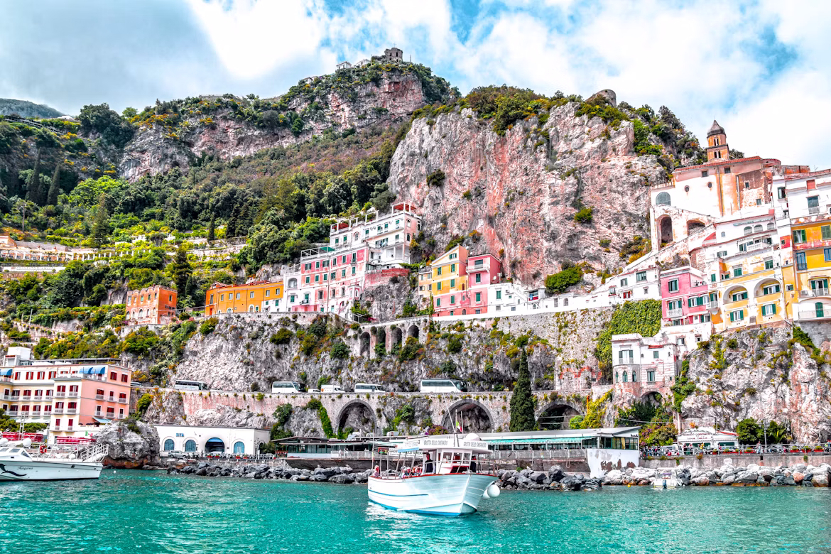 A passenger boat departing from the picturesque coastline of Amalfi with its colorful houses